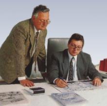 Auf dem Foto sind die beiden damaligen Senior-Chefs Klaus und Hans Peter Traub zu sehen, wie sie gemeinsam über einem Bauprojekt beraten.